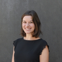 Headshot of Alyssa Van Hofwegen wearing a black top posing against a dark gray background.
